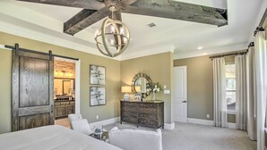 A bedroom with a large bed, a dresser, a mirror, and a chandelier. - Family-Friendly Brookshire Home w/ Game Room! (Brookshire)
