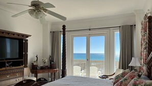 A bedroom with a large bed, a wooden dresser, a television, and a view of the ocean through a sliding door. - Amazing Views! Elegant Gulf Front Home: Elevator, Huge Deck/Walkover, Beach Gear (Pensacola Beach)