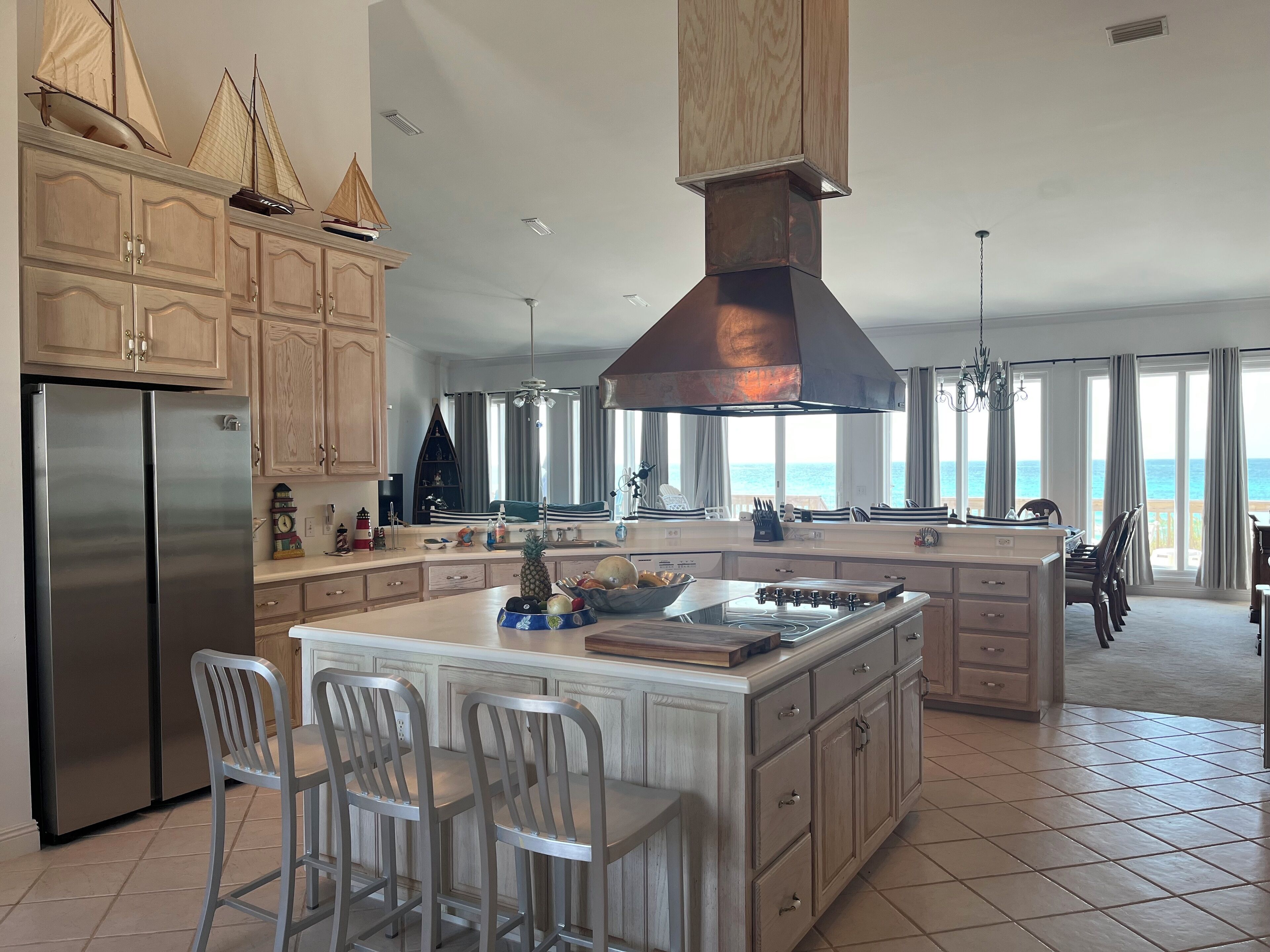 A spacious kitchen with a large island, wooden cabinets, and a view of the ocean.