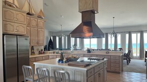 A spacious kitchen with a large island, wooden cabinets, and a view of the ocean. - Amazing Views! Elegant Gulf Front Home: Elevator, Huge Deck/Walkover, Beach Gear (Pensacola Beach)