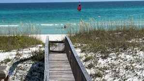 A wooden boardwalk leading to a beach with clear turquoise water and a sailboat in the distance. - Amazing Views! Elegant Gulf Front Home: Elevator, Huge Deck/Walkover, Beach Gear (Pensacola Beach)