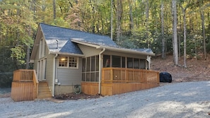 Situated in a wooded area, this cabin features a front porch and a covered entryway.
