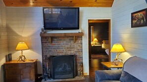 Cozy room with a brick fireplace, comfortable sofa, and two side tables with lamps.