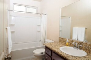 A bathroom with a bathtub, toilet, sink, and a large mirror. - Sparkling & New KING I Close to Necessities (Fresno)