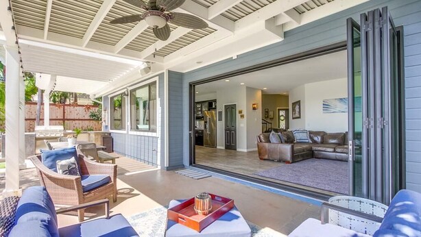 A covered outdoor living area with wicker furniture, a ceiling fan, and a sliding glass door leading to a living room. - Encinitas vacation home- 5 minutes from the beach (Encinitas)