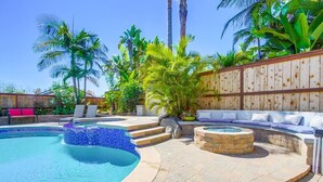 A swimming pool with a hot tub, surrounded by a stone patio and a wooden fence. - Encinitas vacation home- 5 minutes from the beach (Encinitas)