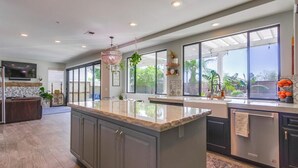 A modern kitchen with large windows, a central island, and a built-in oven. - Encinitas vacation home- 5 minutes from the beach (Encinitas)
