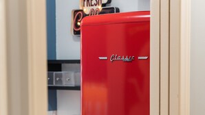 A red vintage refrigerator with a 'Classic' label, a coffee machine, and a 'FRESH' sign on the wall. - Modernized Retro Home In The Montrose (Houston)