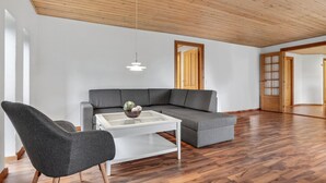 A spacious living area with a gray sectional sofa, a white coffee table, and a gray armchair.