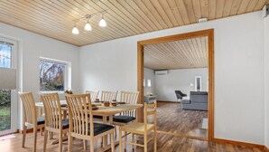 A spacious dining area with a wooden table and chairs, a large mirror, and a view of a living room with a gray sofa.