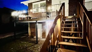 A two-story house with a wooden staircase leading to a balcony. - Stylish 3BR Home Sleeps 8 w/ Grill – Near CrossPlex & Downtown (Birmingham)