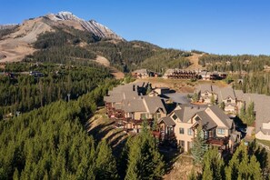 A resort with multiple buildings, surrounded by dense forests and a mountain in the background.