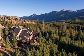 A lodge with multiple cabins surrounded by dense forest and mountains in the background.
