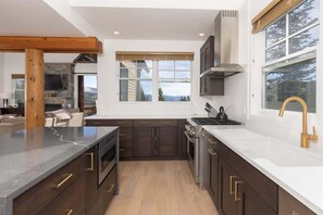 A modern kitchen with dark wood cabinets, a white countertop, and a stainless steel range hood.