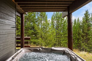 A hot tub under a wooden pergola with a forest view. - Ski-In/Ski-Out 3 Bedroom Moonlight Basin (Big Sky)