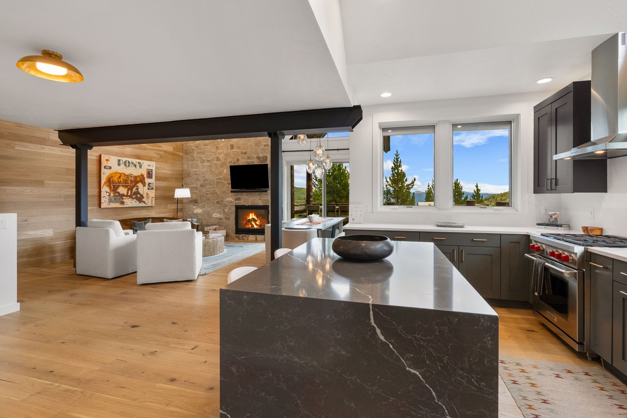 Una cocina moderna con una isla grande, electrodomésticos integrados y una pared de piedra.