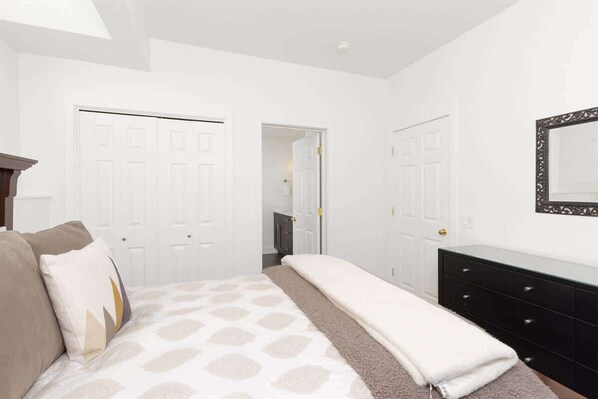 A bedroom with a bed, a dresser, and a mirror on the wall.