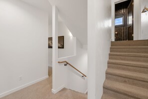 A staircase with a handrail, carpeted steps, and a door with a window.
