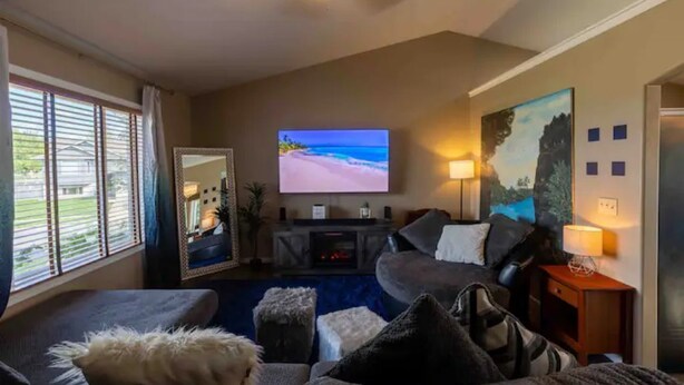 Un salon avec un téléviseur, un canapé, une table basse et un tableau accroché au mur.