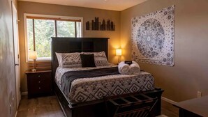 Une chambre à coucher avec un lit, des lampes de chevet, une fenêtre et une tapisserie au mur.