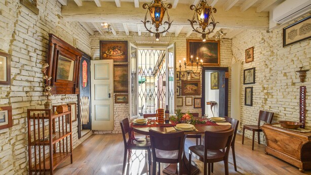 A dining room with a brick wall, wooden furniture, and a chandelier.