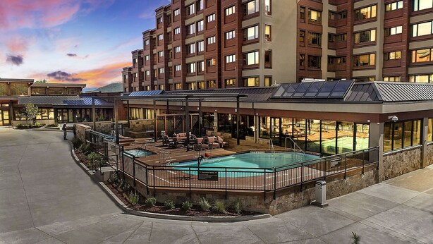 Ein Hotel mit Pool auf dem Dach, Sitzgelegenheiten im Freien und Blick auf die umliegenden Gebäude.
