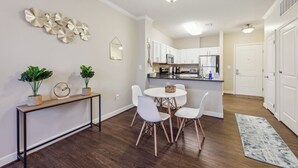 A modern kitchen with white cabinets, a central island, and a dining area with white chairs and a round table. - Getaway | Hidden Gem | Free-Parking (Woodbridge)