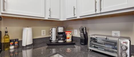 A kitchen with white cabinets, a coffee maker, a toaster, and a knife block.