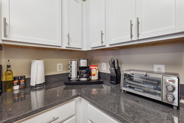 A kitchen with white cabinets, a coffee maker, a toaster, and a knife block.