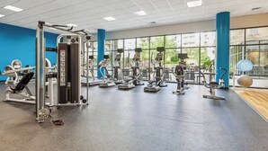 A gym with various exercise equipment, large windows, and a blue accent wall. - Getaway | Hidden Gem | Free-Parking (Woodbridge)
