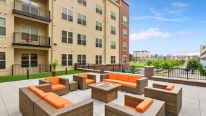 A rooftop patio with wicker furniture and a fire pit, surrounded by a pool and a view of a cityscape. - Getaway | Hidden Gem | Free-Parking (Woodbridge)