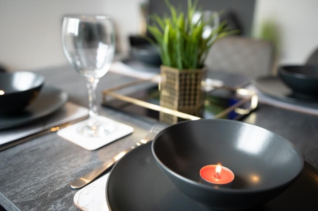 A dining table with a candle, a glass, and a plant.