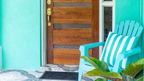 A turquoise wall, a wooden door with a glass panel, a blue chair, and a potted plant. - Entire Condominium Home away from Home with Pool, Near Beach (Nassau)