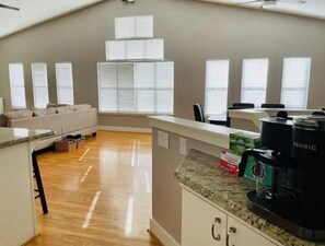 Relax in this inviting living area with a high ceiling, large window, and comfortable sofa.