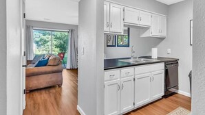 A modern kitchen with white cabinets, a black countertop, and a dishwasher.