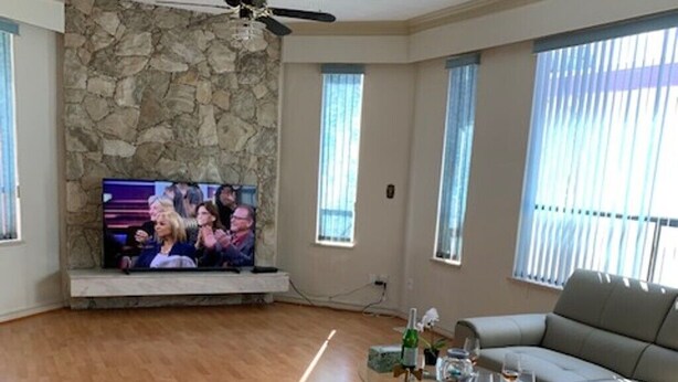 Ein Wohnzimmer mit Steinwand, Flachbildfernseher, Deckenventilator und grauem Sofa.