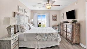 A bedroom with a bed, a dresser, a television, and a ceiling fan. - 3BR @ Grand Beach Resort • Sleeps 8 • Balcony, Pool • Walk to Beach & The Hangout (Gulf Shores)