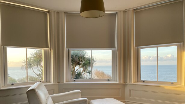 A bedroom with a large bed, two white chairs, a small ottoman, and three windows offering ocean views. - St Catherine's Lookout,  Niton, Isle of Wight (Niton)