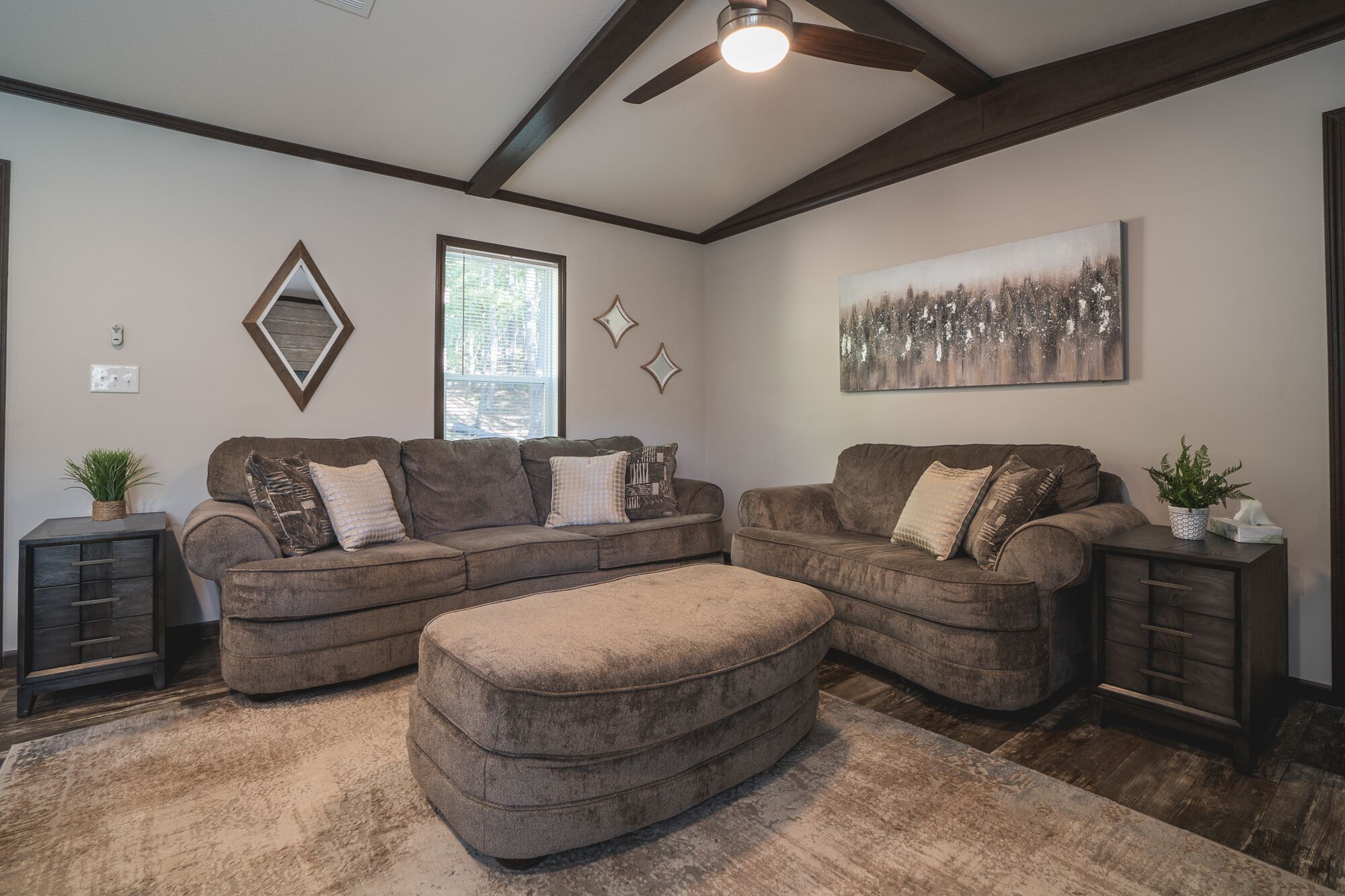 A living room with a sectional sofa, ottoman, and a ceiling fan.