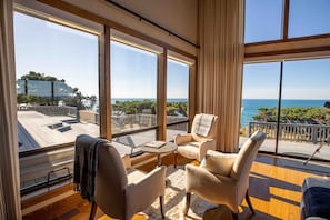 A spacious room with large windows offering a view of the sea and a deck area.