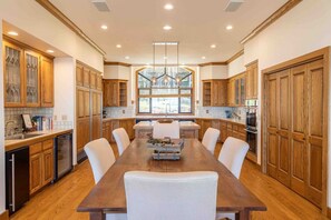 A spacious kitchen with wooden cabinets, a central island, and a large dining table with chairs. - Oceanfront Home Near Bandon Dunes Golf Discounted for Fall & Winter (Bandon)