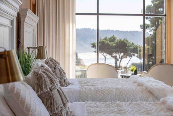 A hotel room with a large window offering a view of trees and hills.
