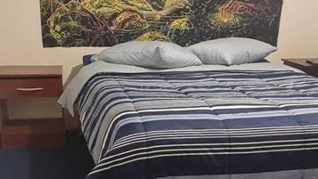 Un lit avec une literie à rayures et un grand tableau abstrait accroché au mur.
