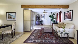A living room with a sofa, ottoman, and a glass coffee table. There is a chair and a dining table with a rug. - The Guest Dahl House of Sedona (Sedona)