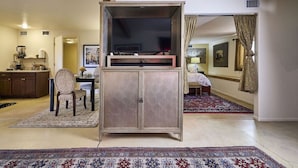 A living room with a TV on a stand, a dining area with a table and chairs, and a kitchen area with cabinets and a sink. - The Guest Dahl House of Sedona (Sedona)