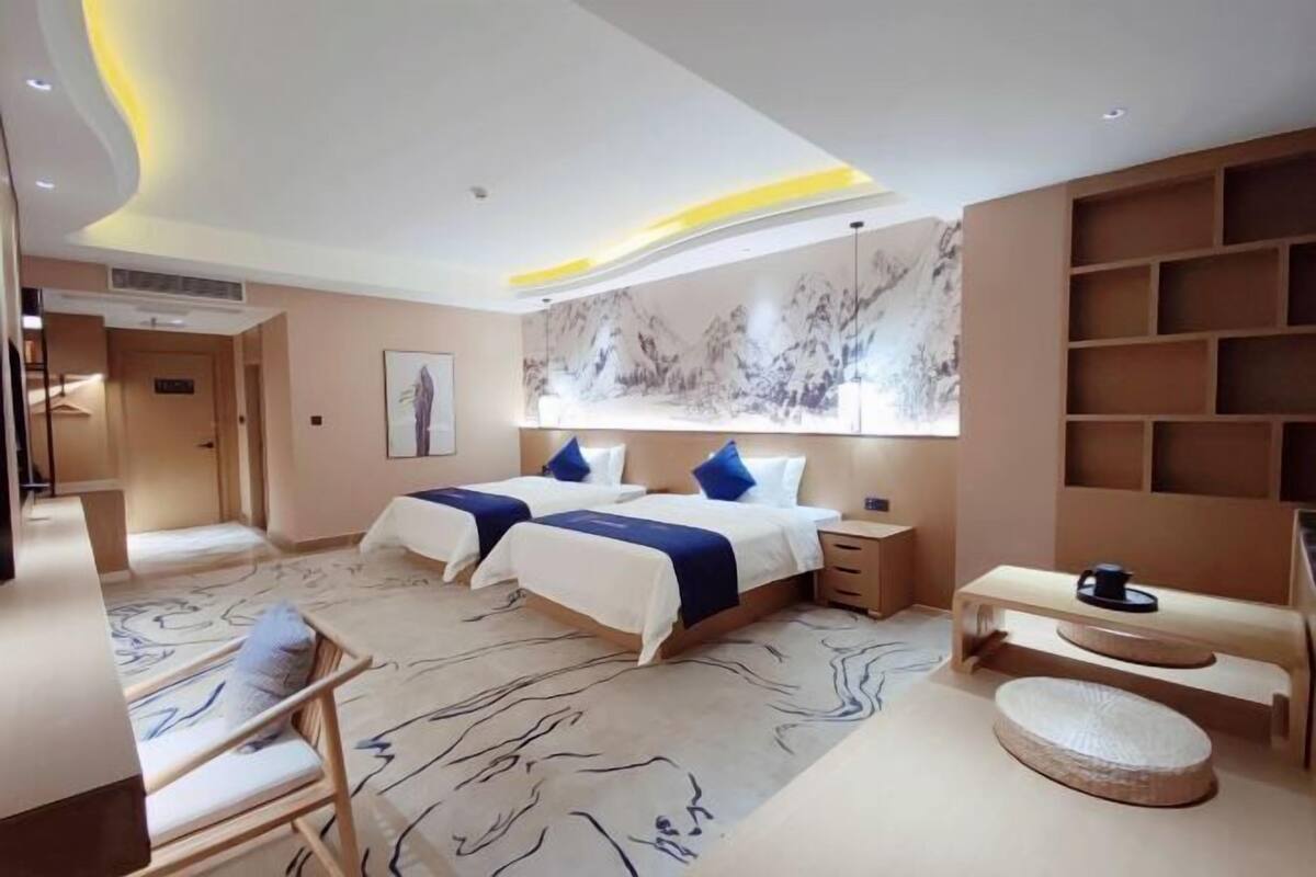 A modern hotel room with a large bed, bedside tables, a desk, and a seating area.