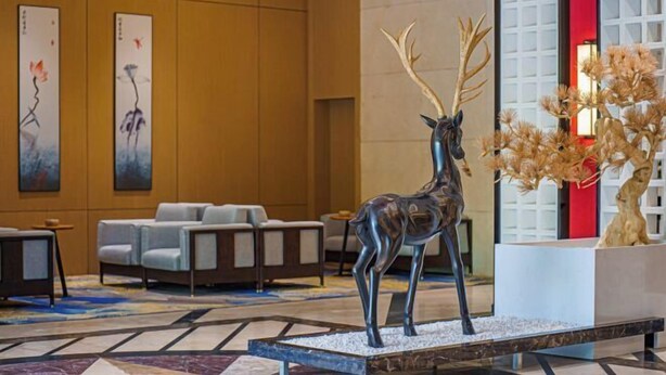 A lobby with a large deer sculpture, seating area, and artwork on the walls.