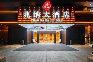 Entrada de hotel com fachada moderna e placa de destaque.