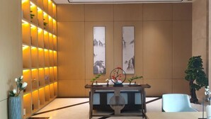 A modern lobby with a wooden reception desk, a wall with illuminated panels, and two framed artworks.