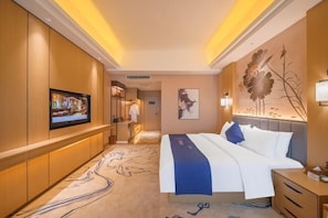 A hotel room with a bed, bedside table, TV, and artwork on the walls.